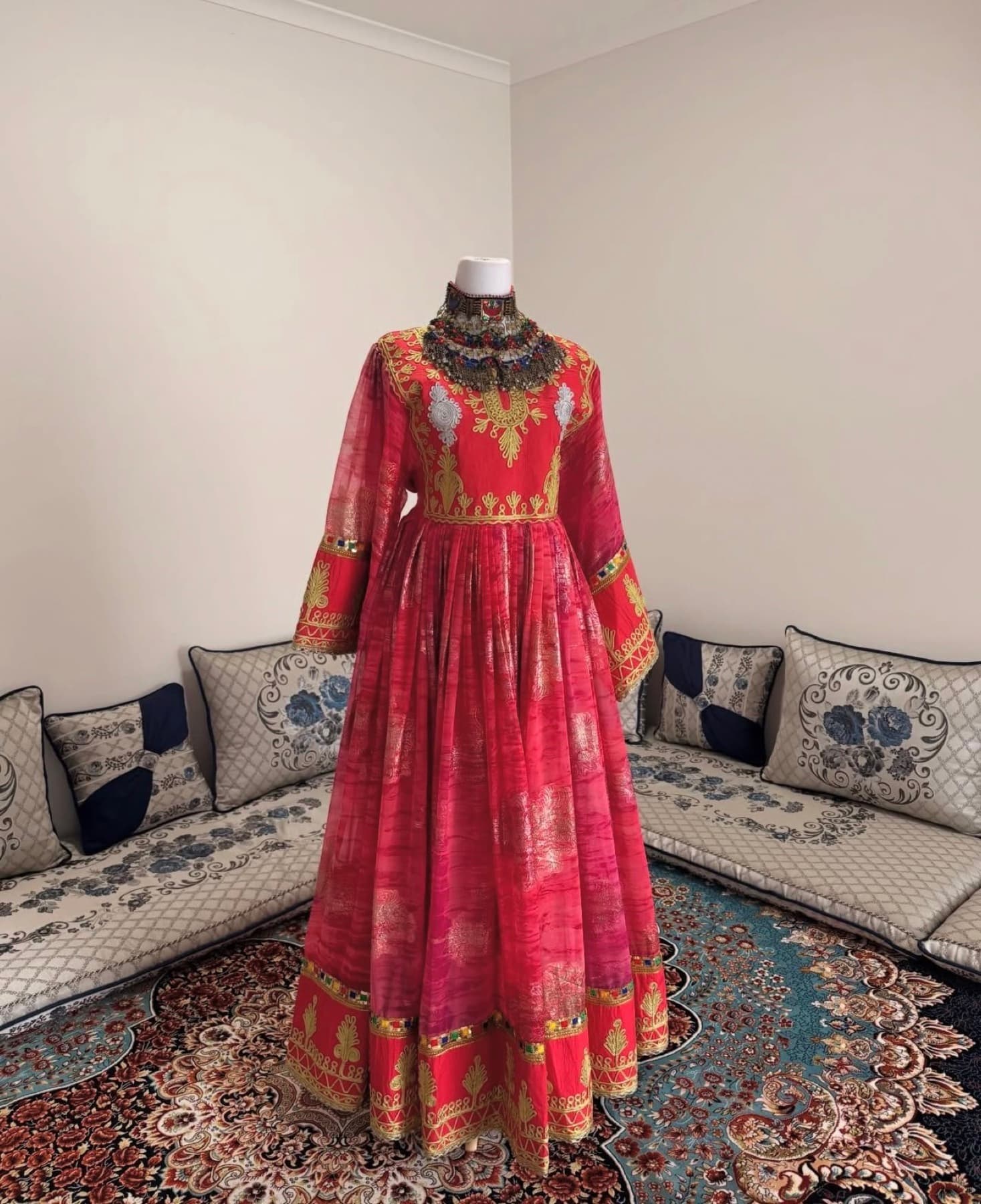 Rose red Afghan dress displayed on a mannequin with gold embroidery.